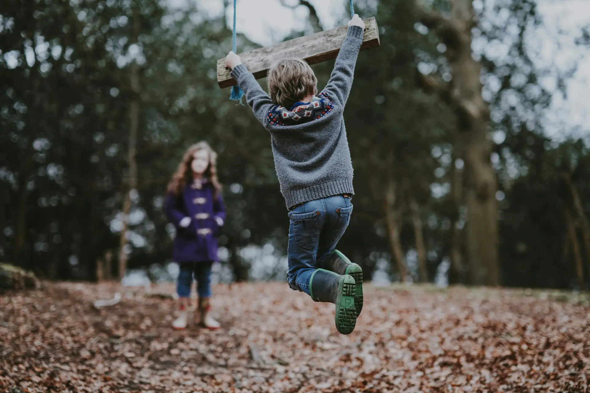 Two young children playing in a forest